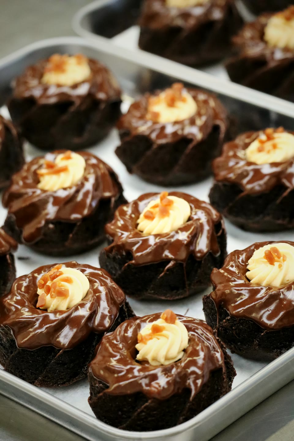 Chocolate bundt cakes glazed with ganache and finished with a swirl of vanilla cream