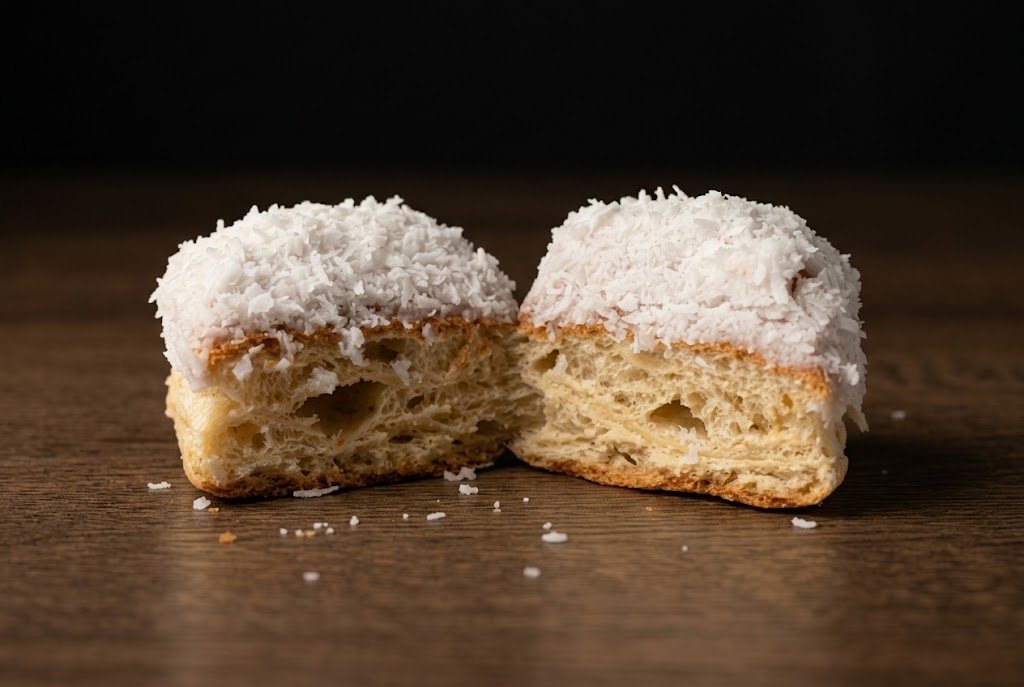 A coconut-iced finger bun cut in half to show the soft crumb