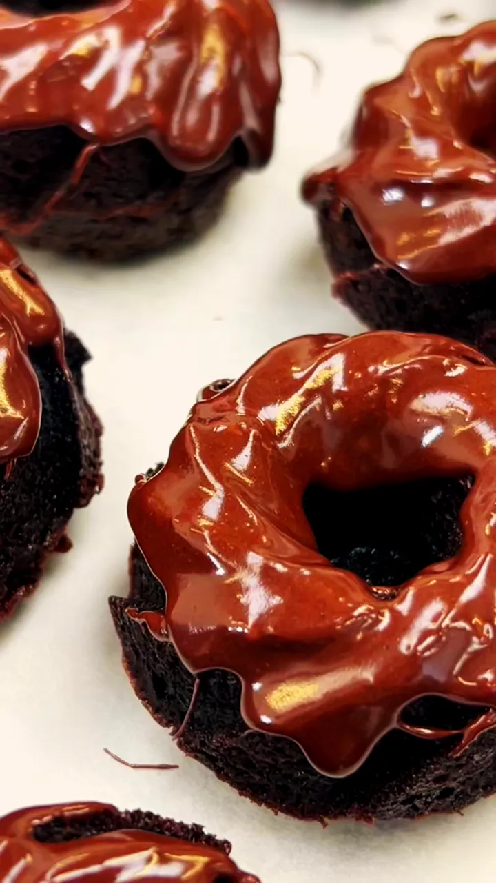 Chocolate bundt cakes freshly glazed with ganache on a white tray
