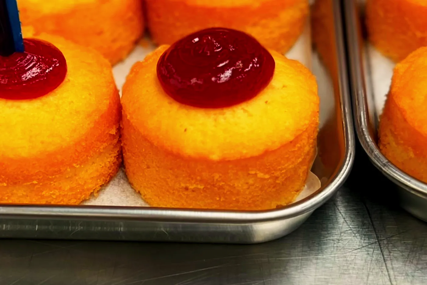 A baker piping raspberry jam into rows of mini sponges